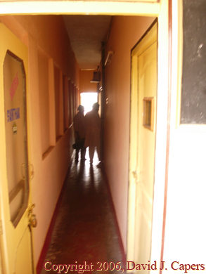 A man sits beside the water, in his village, reflecting.